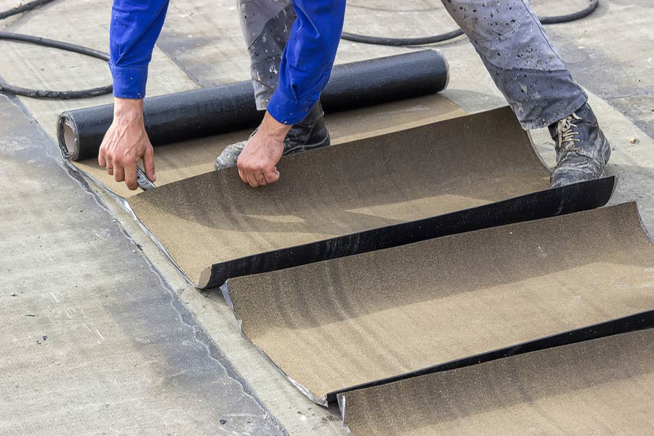 roofing expert unwinding roof coating material atop a home's roof