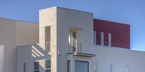 Modern red and white home with flat roof and balcony. 