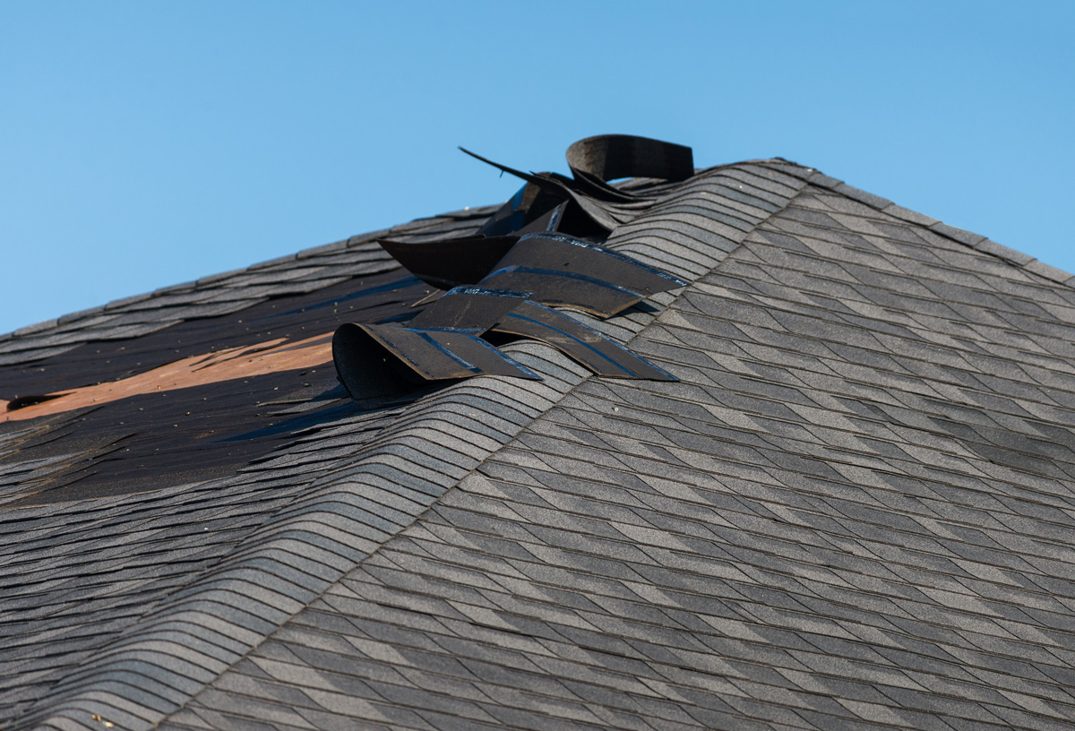  A wind-damaged roof with shingles falling off in El Paso.